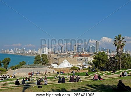 Jaffa, Israel - February 23, 2019: Residents And Tourists Relax In The Amphitheater In Jaffa And Wat