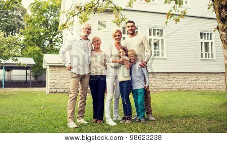 family, happiness, generation, home and people concept - happy family standing in front of house outdoors