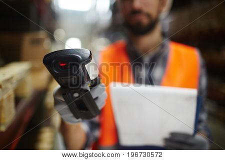 Closeup of bar code scanner in hand of unrecognizable warehouse worker doing inventory of stock