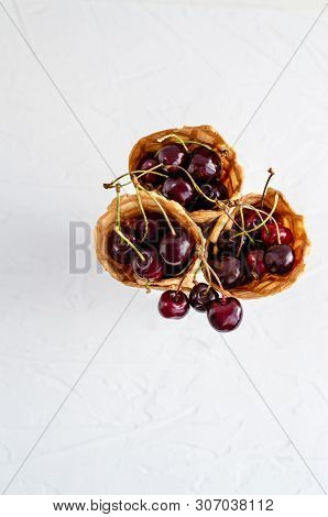 Three Ice Cream Cones Filled With Cherries In A Glass Beaker On A Light White Concrete Background.