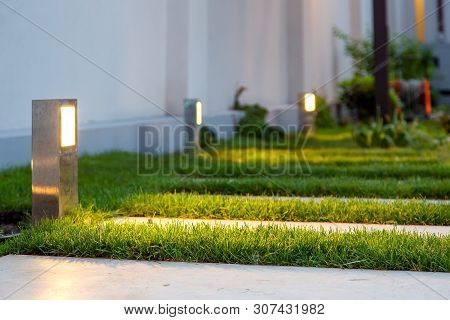 Ground Lantern Lighting Marble Walkway In The Evening Park With A Green Lawn, Closeup Lantern Illumi