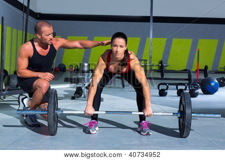 gym personal trainer man with weight lifting bar woman workout in exercise