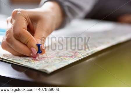 Female Hand Holding Pushpin Showing The Location Of A Destination Point On A Map. Travel Destination