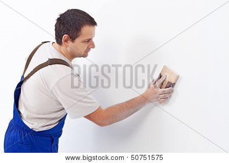 Worker Scrubbing The Wall With Sandpaper