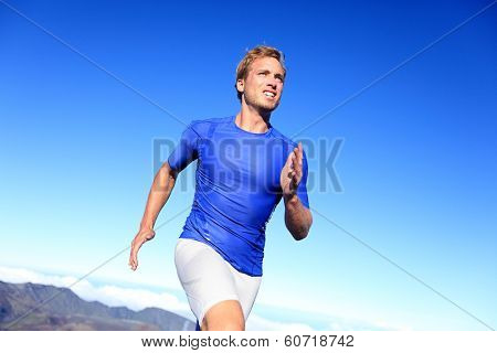 Athlete runner sprinting running to success. Fit male fitness sprinter training in sprint with determination and strength. Handsome athletic man working out outside on blue sky.