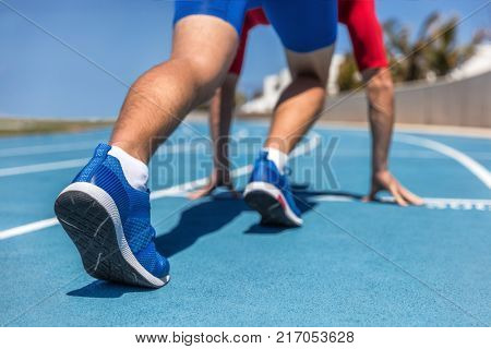 Sprinter waiting for start of race on running tracks at outdoor stadium. Sport and fitness runner man athlete on blue run track with running shoes.