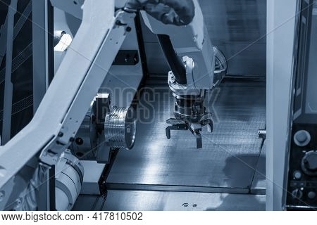 The Robotic Arm Gripping The Metal Part From Cnc Lathe Machine. The Hi-technology Material Handling 