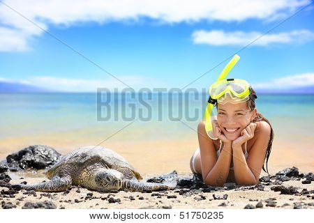 Beach travel woman on Hawaii with sea sea turtle. Snorkeling girl on vacation wearing snorkel smiling happy enjoying blue sky and sun lying next to Hawaiian sea turtles on Big Island, Hawaii, USA.