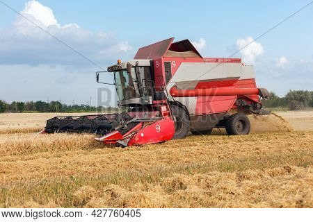 Wheat Harvesting On Field In Summer Season. Combine Harvester Harvests Ripe Wheat. Agriculture. Proc