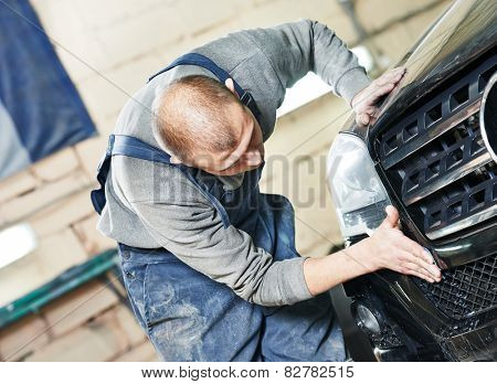 auto mechanic worker sanding polishing bumper car at automobile repair and renew service station shop by sandpaper