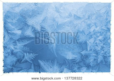 Bright blue frost pattern on a window glass in a white frame (as an abstract winter background) retro style