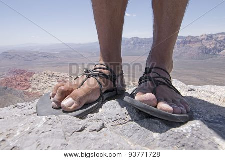 Rugged Feet In Primitive Sandals On Mountain