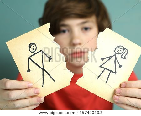 sad preteen boy unhappy about parents divorce hold man and woman paper drawing torn apart