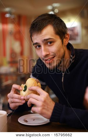 Hamburguesa de joven comiendo en el restaurante de comida rápida. DOF de poca profundidad.