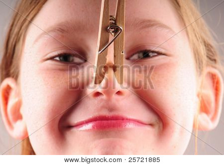 Young girl with clothespin on nose