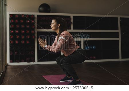 Image Of Sporty Athletic Woman In Sneakers And Tracksuit Squatting Doing Sit-ups In Gym. Side View O