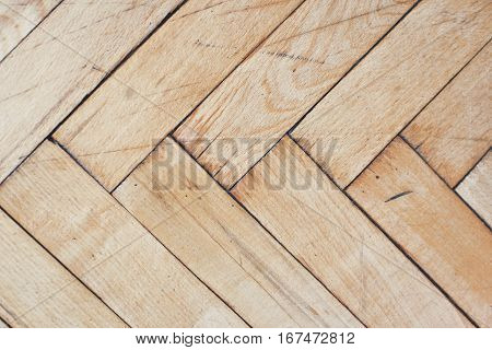 Close top view on distressed brushed parquet floor with geometric mosaic of wood pieces used for decorative effect. Wood block patterns for flooring in herringbone mosaic