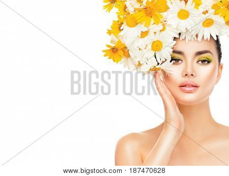 Beauty Girl with Daisy Flowers Hair Style touching her face skin. Beautiful Model woman with Blooming chamomile flowers on her head. Nature Hairstyle. Summer. Holiday Creative Makeup. Fashion Make up