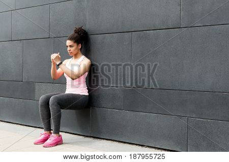 Athlete doing wall squat on city street