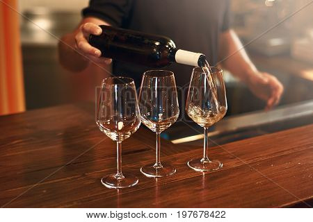 Sommelier pours pinot gris wine in glasses for degustation