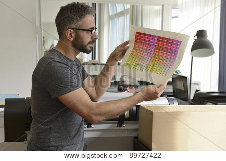 Printing industry: Graphic designer checks the color with color swatch.