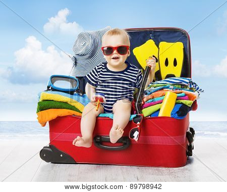 Baby In Travel Suitcase. Kid Inside Luggage Packed For Vacation Full Of Child Clothes