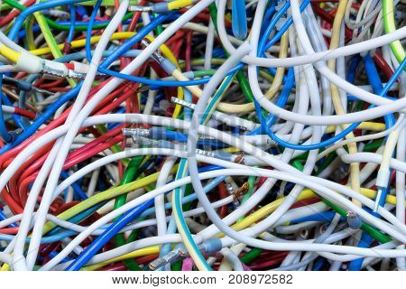 The bunch of electric wires of different colors with cable lugs. Wires and cables are very much mixed up and intertwined. Flexible wire with copper conductor. Disorder and chaos.