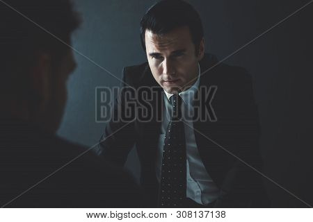 Detective Interviewing Suspect Or Criminal Man In Interrogation Room