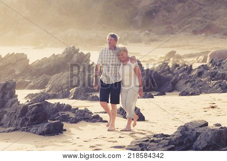 lovely senior mature couple on their 60s or 70s retired walking happy and relaxed on beach sea shore in romantic aging together and retirement husband and wife lifestyle concept