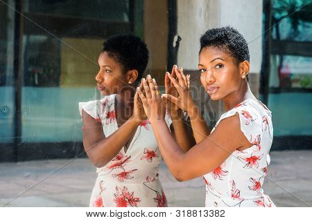 Young African American Woman With Short Afro Hairstyle, Standing By Mirror In New York, Hands Touchi