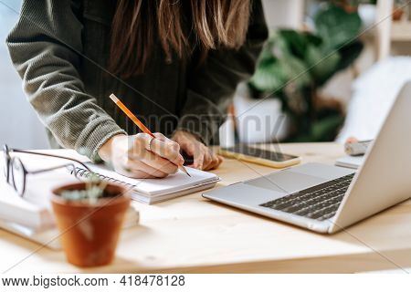 Distance Learning Online Education And Work. Business Woman With Plants Writes In Notebook. Cropped 