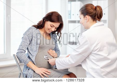 pregnancy, gynecology, medicine, health care and people concept - gynecologist doctor with stethoscope listening to pregnant woman baby heartbeat at hospital