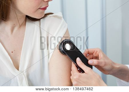 Dermatologist examining birthmarks and moles on a female patient (examination of birthmarks)