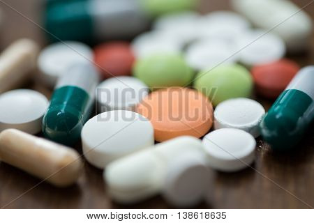 addiction, medication, medicine and substance abuse concept - close up of different drugs in pills and capsules on table