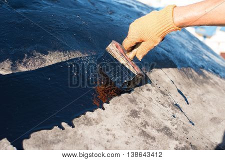 Roofer cover the concrete base polymer modified bitumen waterproofing primer. A worker brushes cover concrete bitumen-rubber primer.