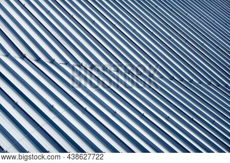 Corrugated metal profile roof installed on a barn house. The roof of corrugated sheet. Roofing of metal profile wavy shape. Modern roof made of metal. Metal roofing.                              