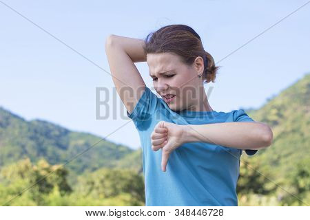 Disgusted Girl, Young Woman Looking At Sweaty T-shirt, Sniffing Her Wet Unclean Armpits, Feeling Bad