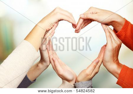 Human hands in heart shape on bright background