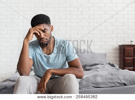 Bad Mood In Morning. Young Depressed African-american Man Sitting On Bed And Consider About Problems