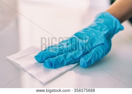 Surface disinfecting home cleaning with sanitizing antibacterial wipes protection against COVID-19 spreading wearing medical blue gloves. Sanitize surfaces prevention in hospitals and public spaces.