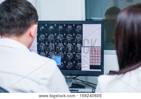 Doctors Consider And Discuss Magnetic Resonance Image (mri) Of The Brain. Back View, Selective Focus