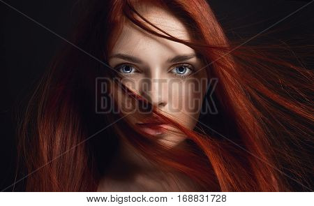 Sexy beautiful redhead girl with long hair. Perfect woman portrait on black background. Gorgeous hair and deep eyes. Natural beauty clean skin facial care and hair. Strong and thick hair. Flower