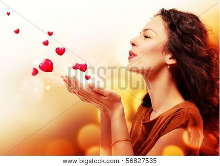 Beauty Young Woman Blowing Hearts from her Hands. St. Valentines Day Concept. Beautiful Girl in Love. Valentine art design. Valentines Gift