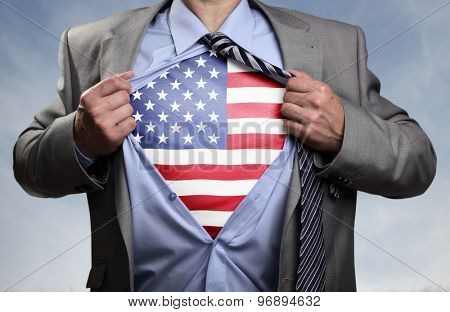 Businessman in classic superhero pose tearing his shirt open to reveal t shirt with the American flag concept for patriotism, freedom and national pride