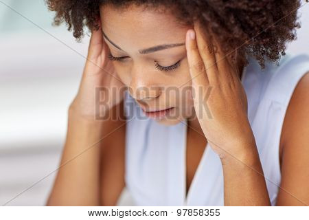 people, emotions, stress and health care concept - unhappy african american young woman touching her head and suffering from headache