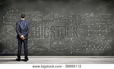 Business person standing against the blackboard with a lot of data written on it