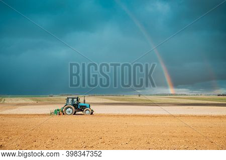 Old Tractor Plowing Field In Spring Season. Beginning Of Agricultural Spring Season. Cultivator Pull