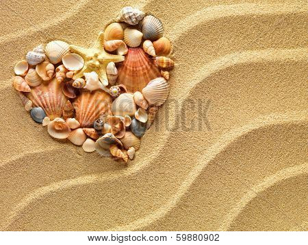 Heart made of sea shells and the starfish lying on a beach sand summer background