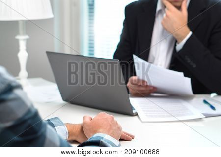 Job interview or meeting with bank worker in office. Business man considering. Discussion about loan, mortgage or insurance. Human resources conversation. Hiring or getting fired. Thoughtful man.