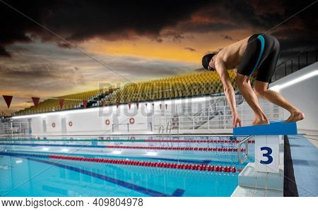 Professional young muscular swimmer jumping from starting block in a swimming pool